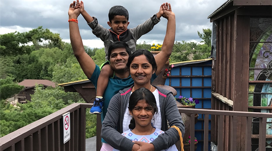 Venkat with his family Venkat with his son on his shoulder with his wife and daughter standing in front of him