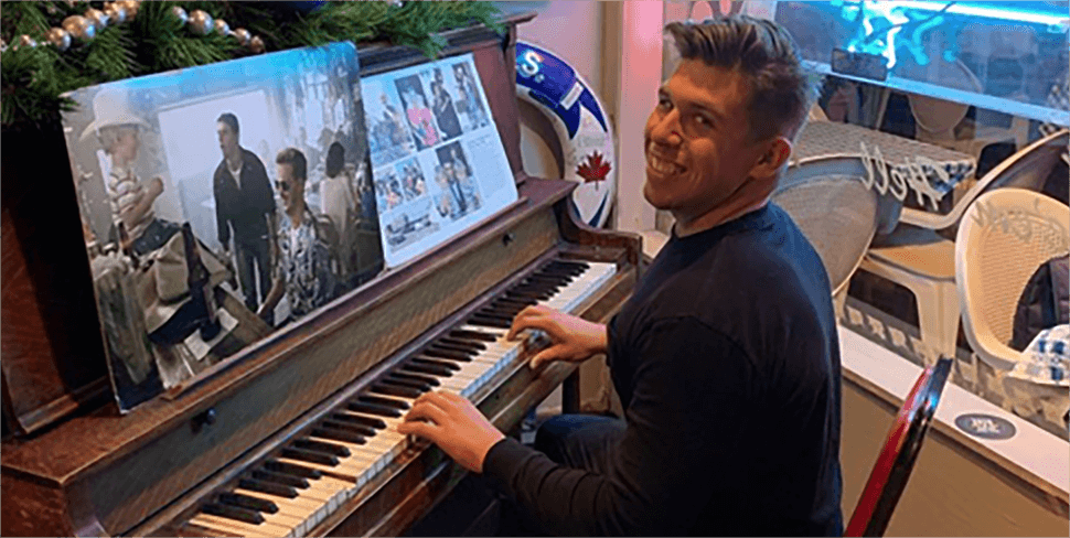 Brandon smiling and playing the piano