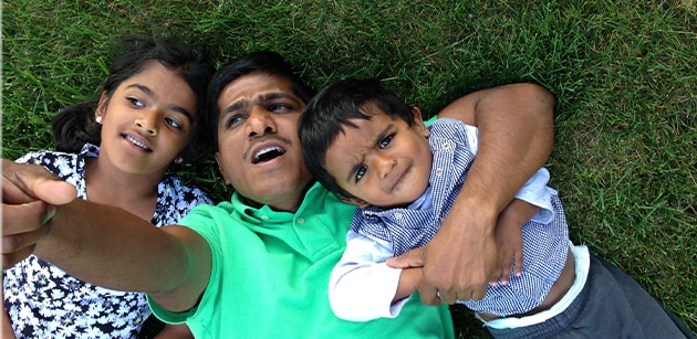 Venkat lying in the grass with his children