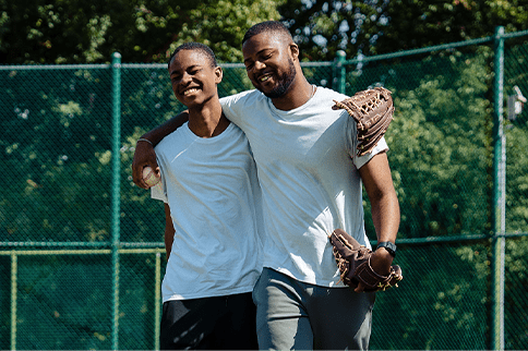 Austin smiling in baseball gloves and arms around his brother