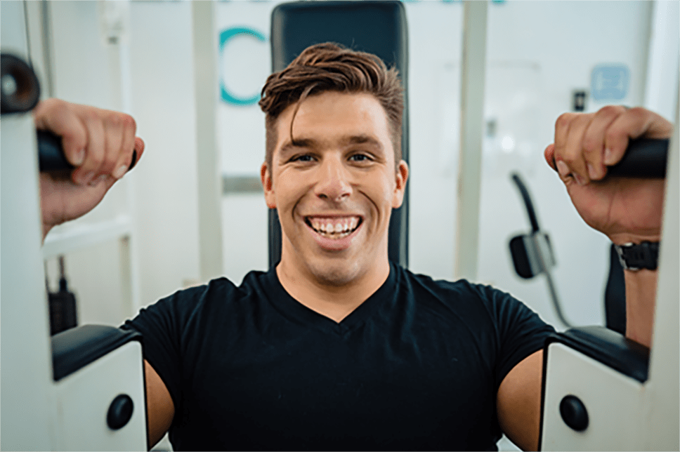 Brandon smiling on gym equipment