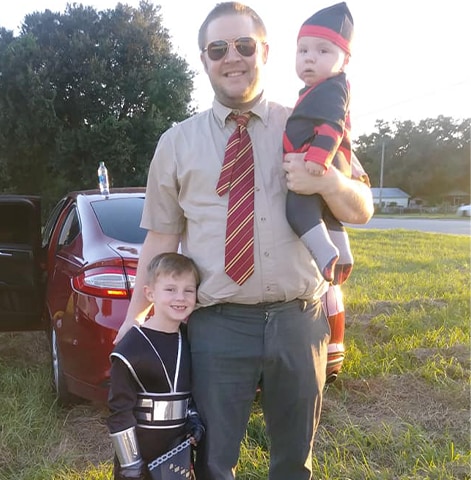 Ryan posing outside with his sons in costume